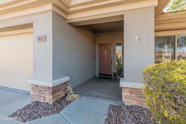 entrance to property with stucco siding and a garage