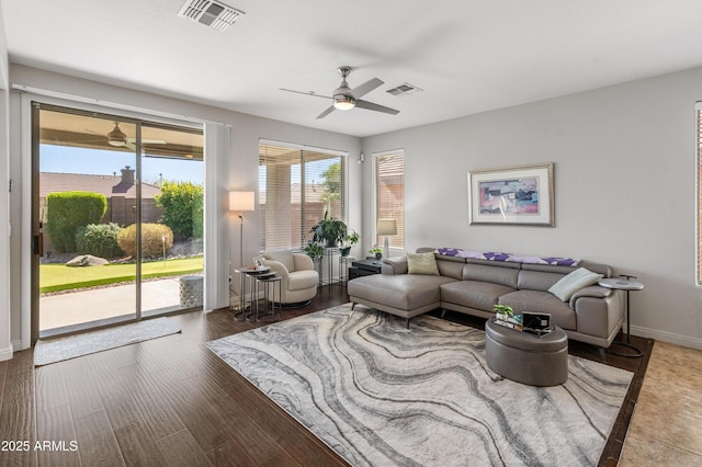 living room featuring visible vents, baseboards, wood finished floors, and a ceiling fan