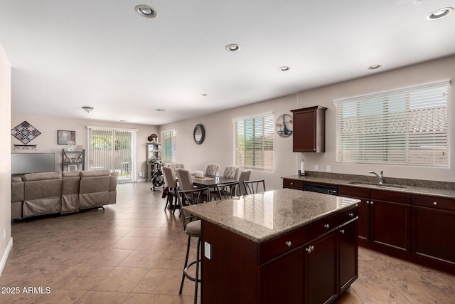 kitchen featuring recessed lighting, a center island, a sink, open floor plan, and a kitchen breakfast bar