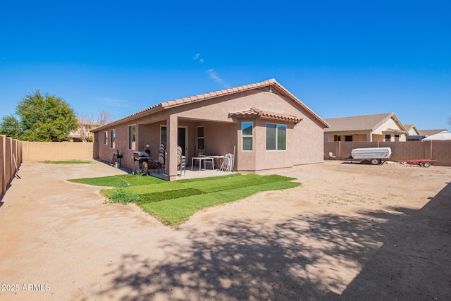 rear view of property with a patio, a tiled roof, stucco siding, and a fenced backyard