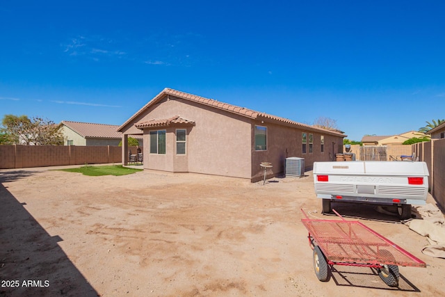 rear view of house featuring central AC unit, a tiled roof, stucco siding, and fence