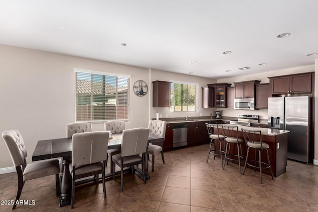 kitchen featuring dark brown cabinetry, a kitchen island, a kitchen bar, appliances with stainless steel finishes, and recessed lighting