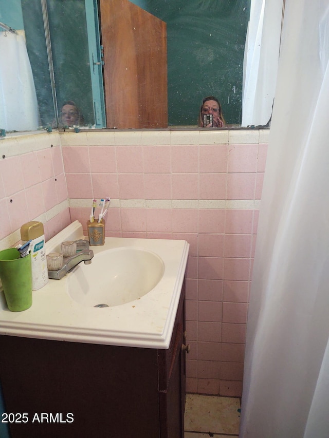 bathroom with vanity and tile walls