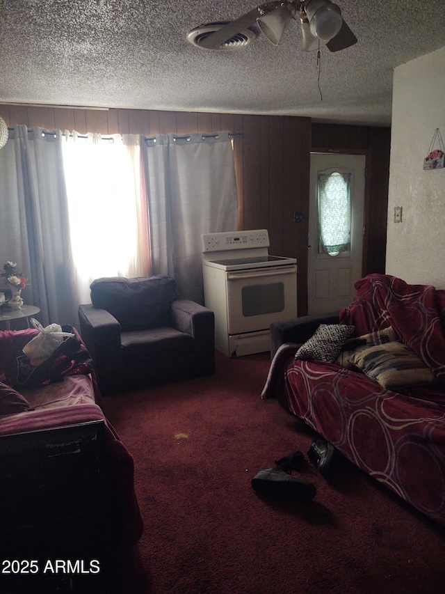 living room featuring ceiling fan, carpet floors, and a textured ceiling