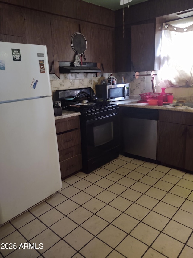 kitchen with stainless steel appliances, light tile patterned flooring, and dark brown cabinets