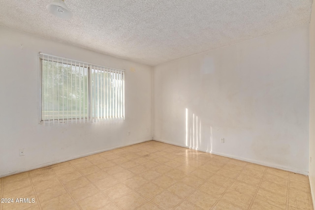 6120 N 30th Ave, Phoenix, AZ 85017 - empty room featuring a textured ceiling, tile patterned floors, and baseboards