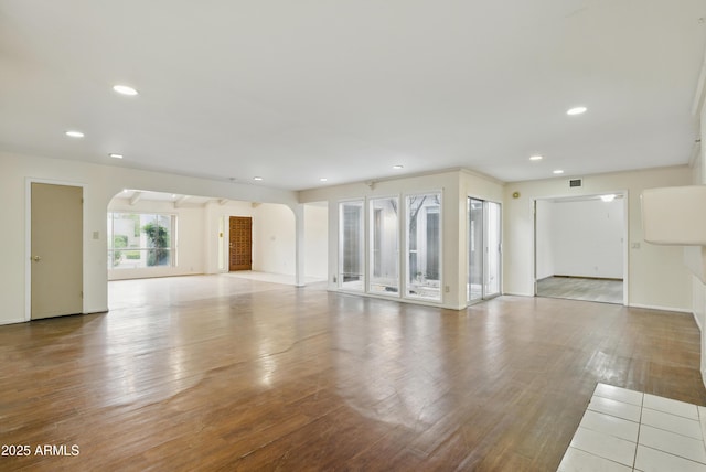 8411 E Via De Jardin, Scottsdale, AZ 85258 - unfurnished living room with arched walkways, wood finished floors, and recessed lighting