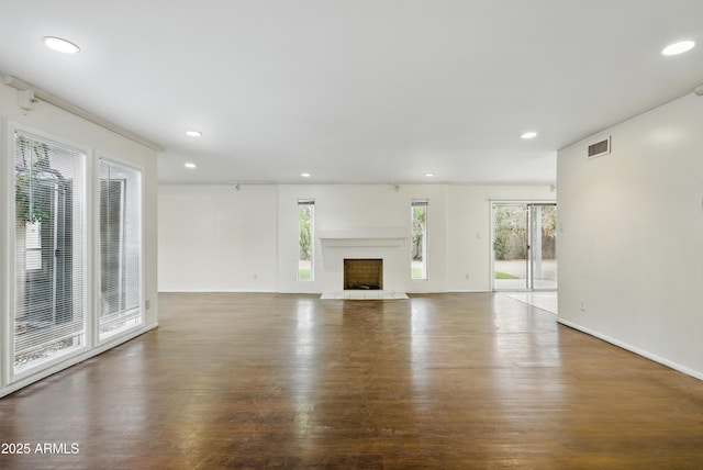 8411 E Via De Jardin, Scottsdale, AZ 85258 - unfurnished living room with healthy amount of natural light, wood finished floors, recessed lighting, and a fireplace with raised hearth