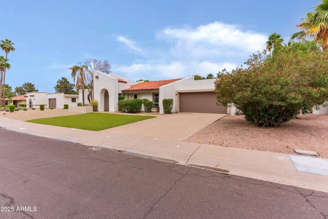 8411 E Via De Jardin, Scottsdale, AZ 85258 - mediterranean / spanish-style home featuring stucco siding, a garage, concrete driveway, a tiled roof, and a front yard