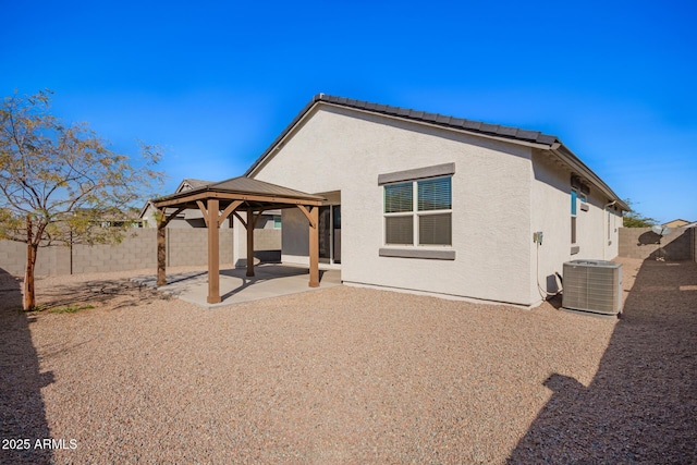 rear view of property featuring central AC unit, a fenced backyard, a gazebo, a patio area, and stucco siding