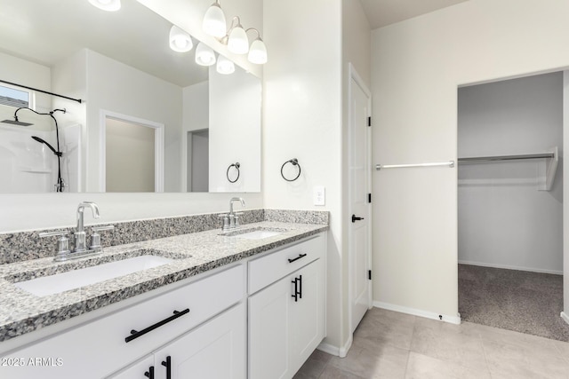 full bathroom featuring a spacious closet, double vanity, a sink, and baseboards