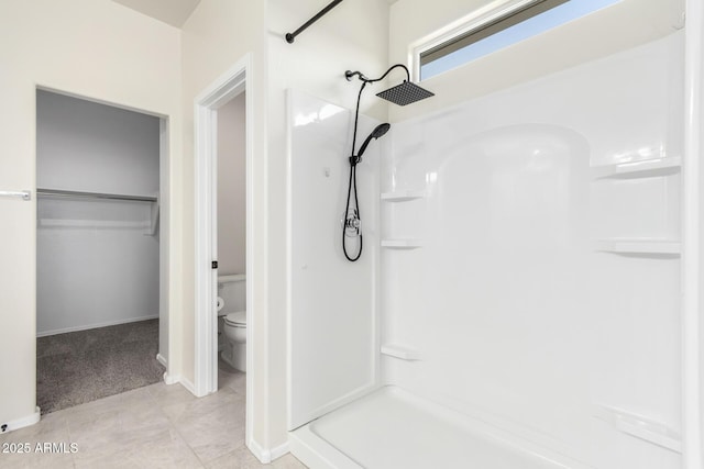 full bathroom featuring toilet, a stall shower, a walk in closet, and tile patterned floors