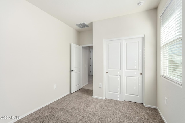 unfurnished bedroom featuring baseboards, visible vents, carpet flooring, and multiple windows