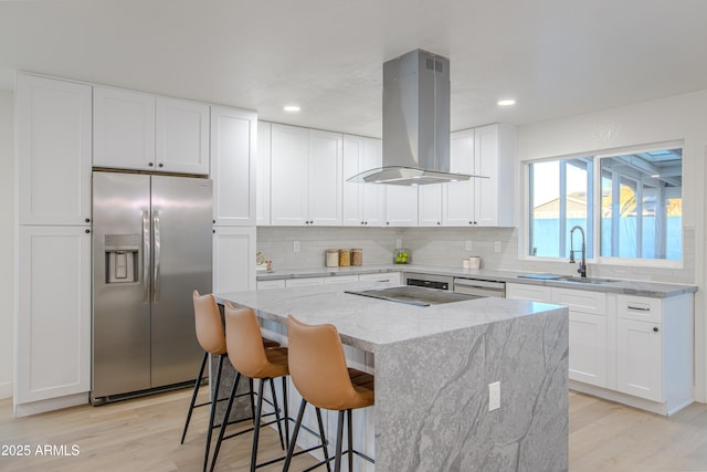 kitchen featuring sink, white cabinetry, island range hood, appliances with stainless steel finishes, and a kitchen island