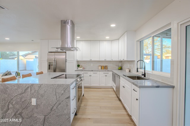 kitchen featuring sink, white cabinetry, island range hood, light wood-type flooring, and appliances with stainless steel finishes