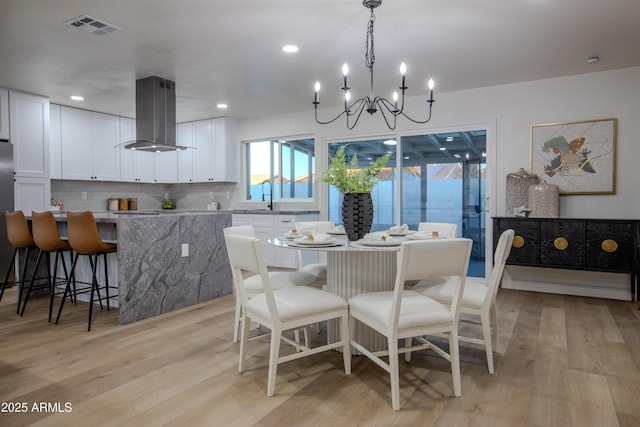 dining space featuring an inviting chandelier, sink, and light hardwood / wood-style flooring