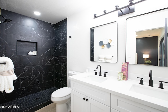 bathroom featuring vanity, toilet, and a tile shower