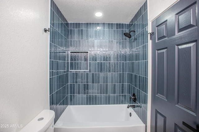 bathroom with tiled shower / bath, a textured ceiling, and toilet