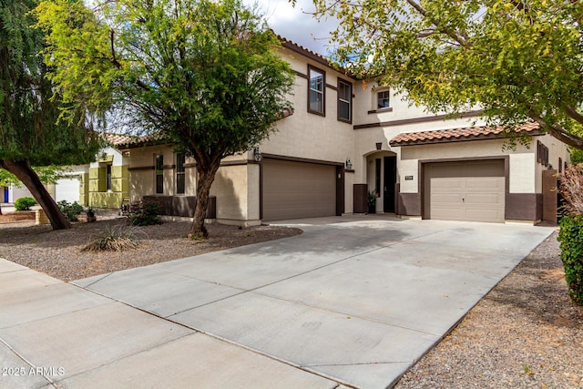 mediterranean / spanish house featuring a tile roof, a garage, driveway, and stucco siding