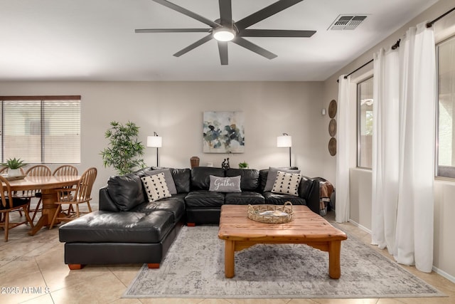 living area with light tile patterned floors, visible vents, baseboards, and ceiling fan