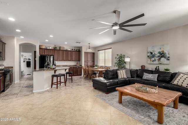 living room with arched walkways, light tile patterned floors, recessed lighting, and a ceiling fan