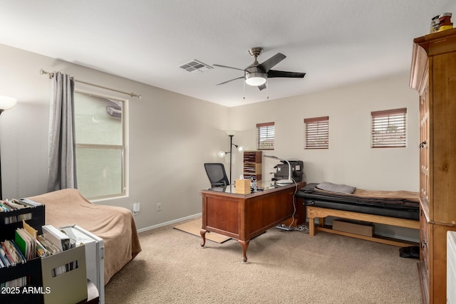 office area featuring visible vents, baseboards, light colored carpet, and a ceiling fan