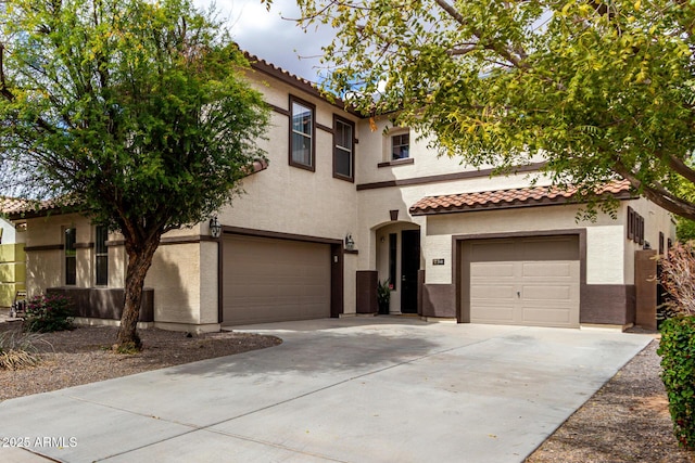 mediterranean / spanish-style home featuring a tiled roof, a garage, concrete driveway, and stucco siding