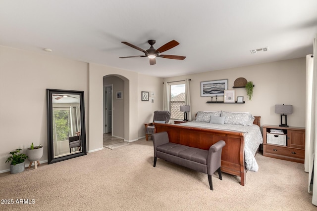 bedroom featuring visible vents, baseboards, light colored carpet, arched walkways, and a ceiling fan