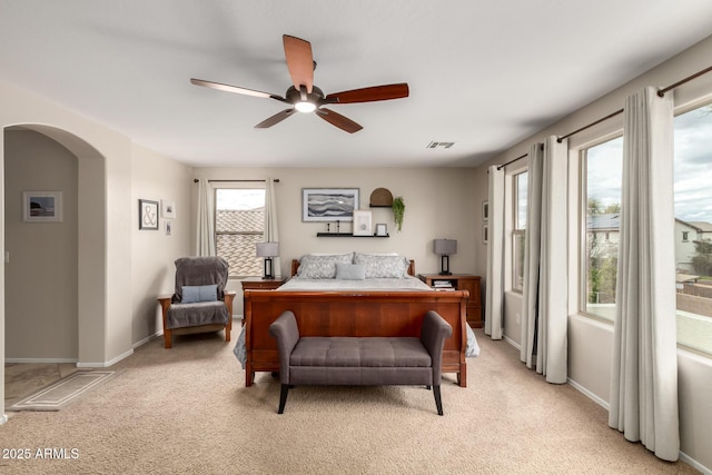 bedroom with arched walkways, visible vents, light carpet, and a ceiling fan