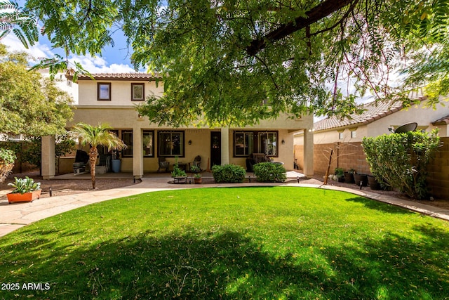 back of property with stucco siding, fence, a yard, a patio area, and a tiled roof