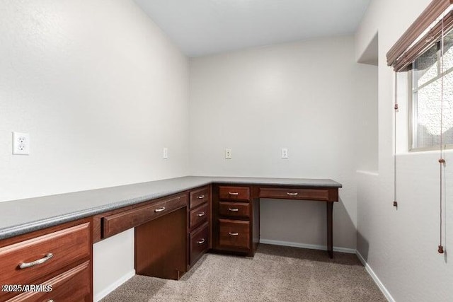 unfurnished office with light colored carpet, baseboards, and built in study area