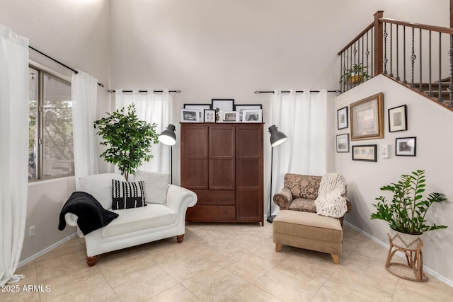 sitting room with light tile patterned floors, baseboards, and a towering ceiling