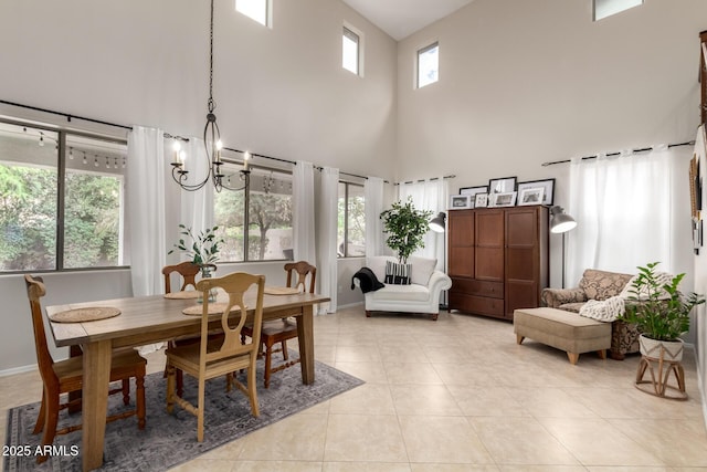 dining area featuring light tile patterned floors, baseboards, a notable chandelier, and a high ceiling