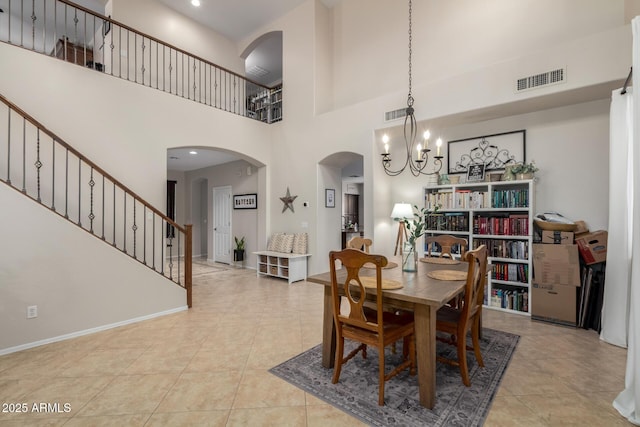 tiled dining space with visible vents, arched walkways, a chandelier, and stairs