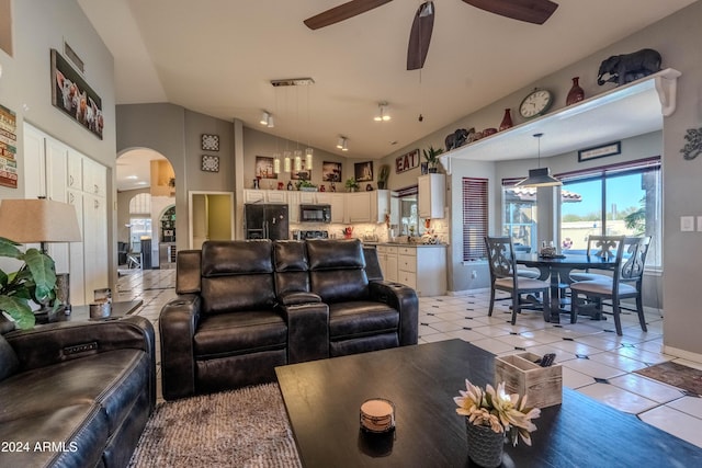 living room with ceiling fan, light tile patterned flooring, and vaulted ceiling