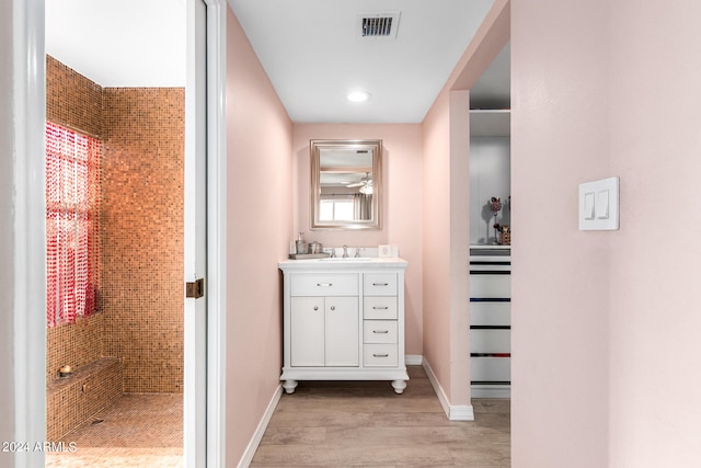 bathroom featuring hardwood / wood-style flooring, vanity, and tiled shower