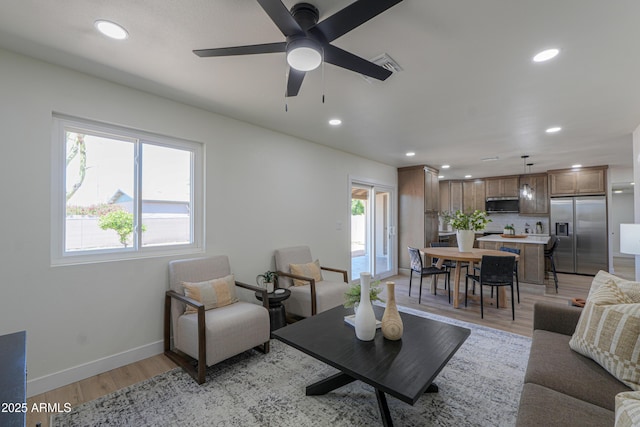living room featuring baseboards, ceiling fan, recessed lighting, and light wood-style flooring