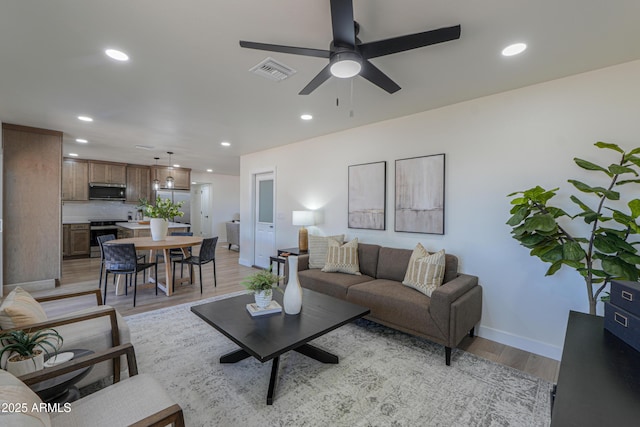 living room with ceiling fan, visible vents, light wood-type flooring, baseboards, and recessed lighting