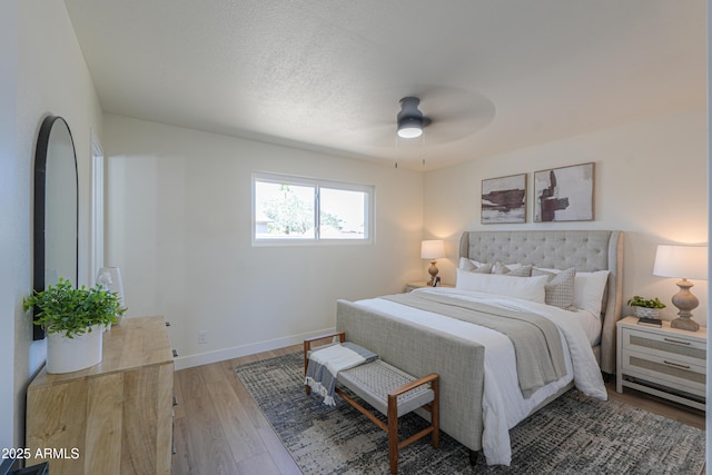 bedroom with light wood-style floors, baseboards, a ceiling fan, and a textured ceiling