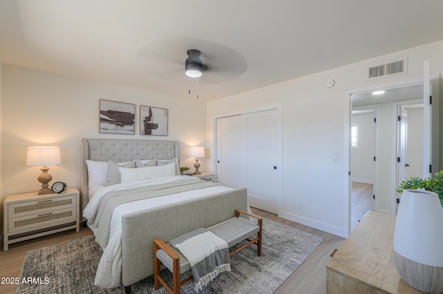 bedroom featuring a ceiling fan, visible vents, baseboards, a closet, and light wood finished floors