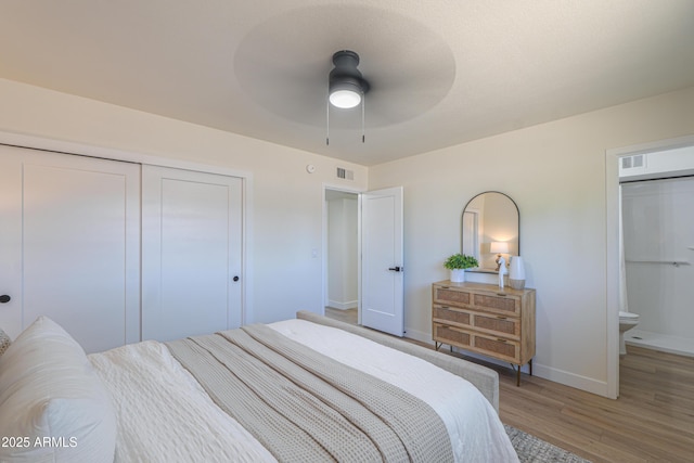 bedroom featuring baseboards, visible vents, wood finished floors, and a closet