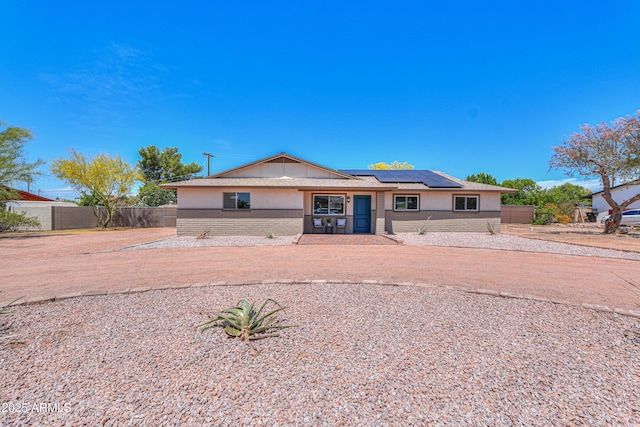 single story home featuring fence, stucco siding, solar panels, and brick siding