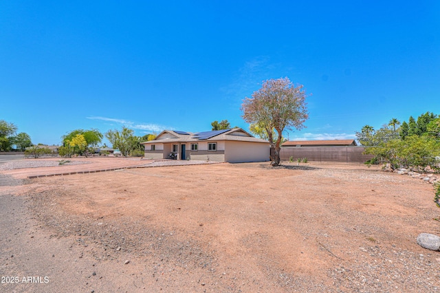 view of front of home featuring fence and solar panels