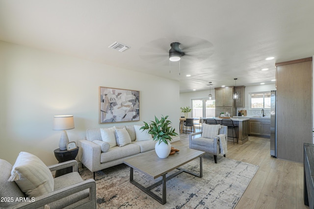 living room featuring a ceiling fan, visible vents, recessed lighting, and light wood-style floors