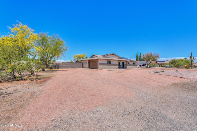 ranch-style home with a garage, fence, and dirt driveway