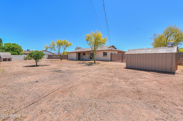rear view of property featuring a fenced backyard, a shed, and an outbuilding