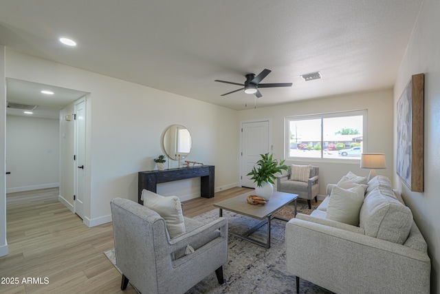 living room featuring visible vents, baseboards, recessed lighting, a ceiling fan, and light wood-style flooring