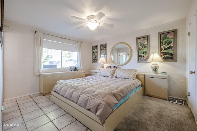 tiled bedroom featuring ceiling fan and brick wall