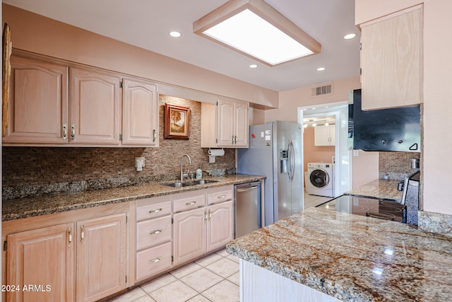 kitchen featuring light stone countertops, light brown cabinetry, stainless steel appliances, sink, and washer / dryer