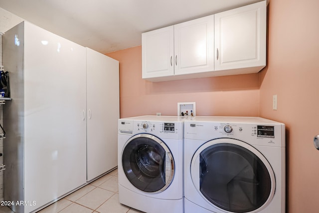 laundry room with washing machine and dryer, light tile patterned flooring, and cabinets